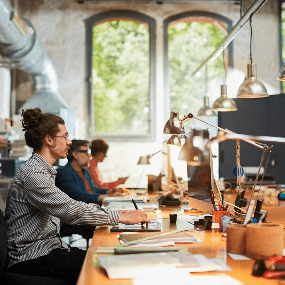 Creatie marketing colleagues sit at a communal desk with lamps